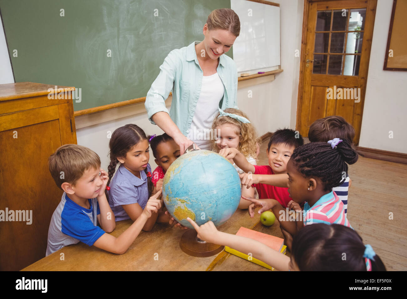 Cute pupils and teacher in classroom with globe Stock Photo - Alamy