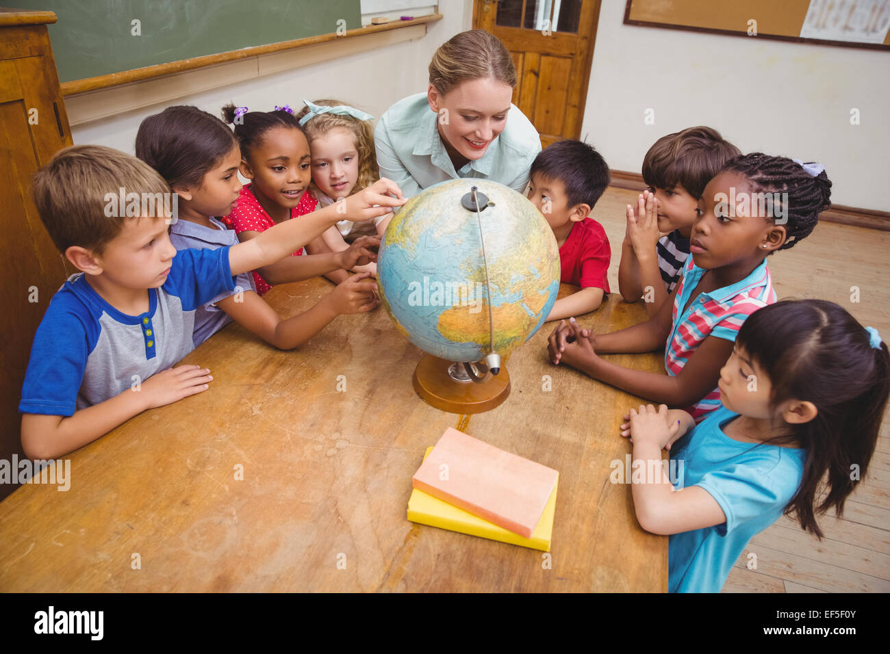 Cute pupils and teacher in classroom with globe Stock Photo - Alamy