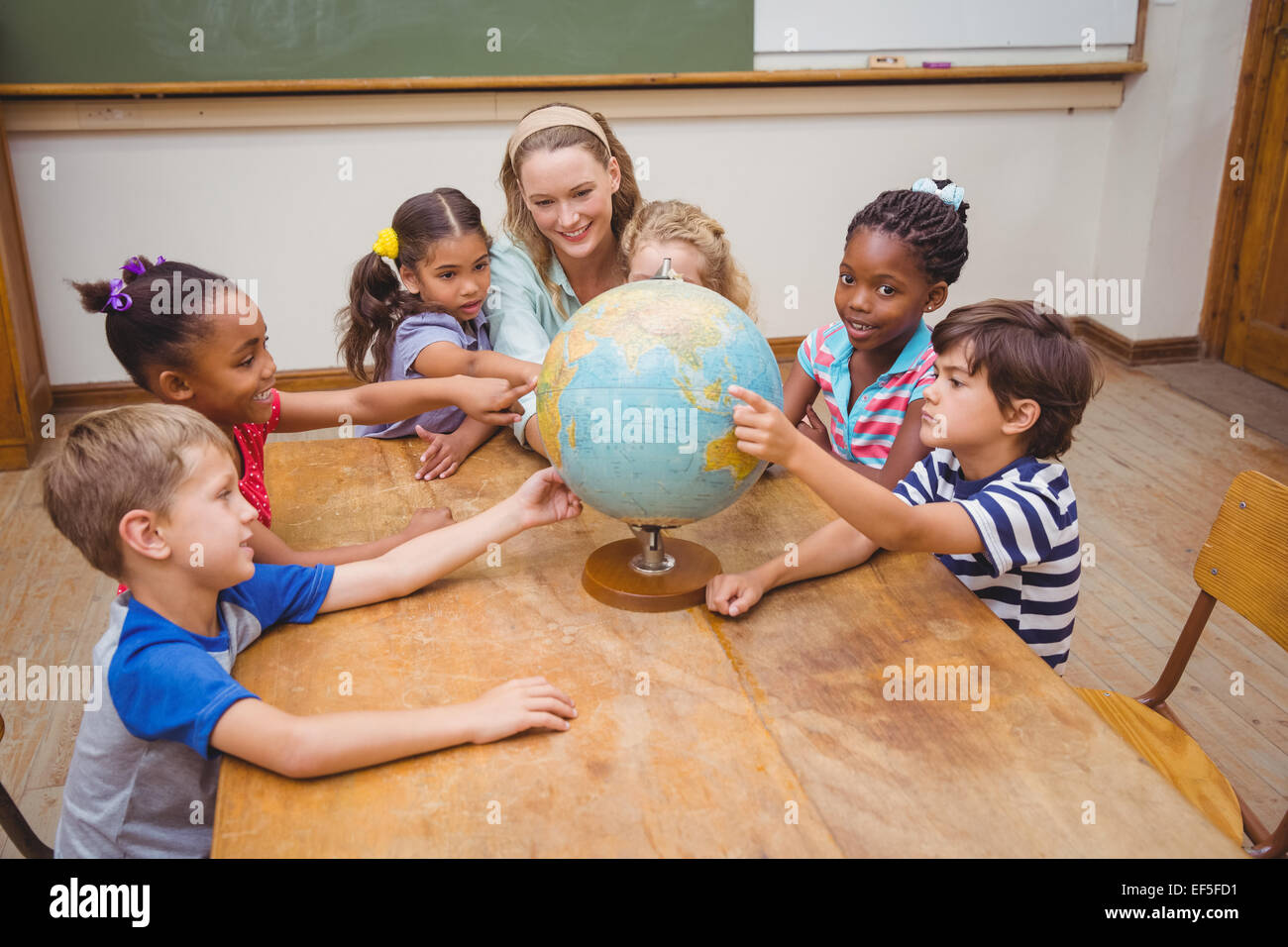 Cute pupils and teacher in classroom with globe Stock Photo - Alamy