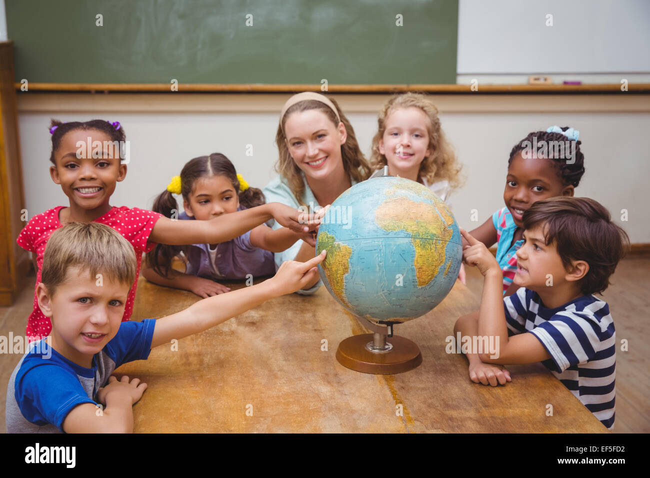 Cute pupils and teacher in classroom with globe Stock Photo - Alamy