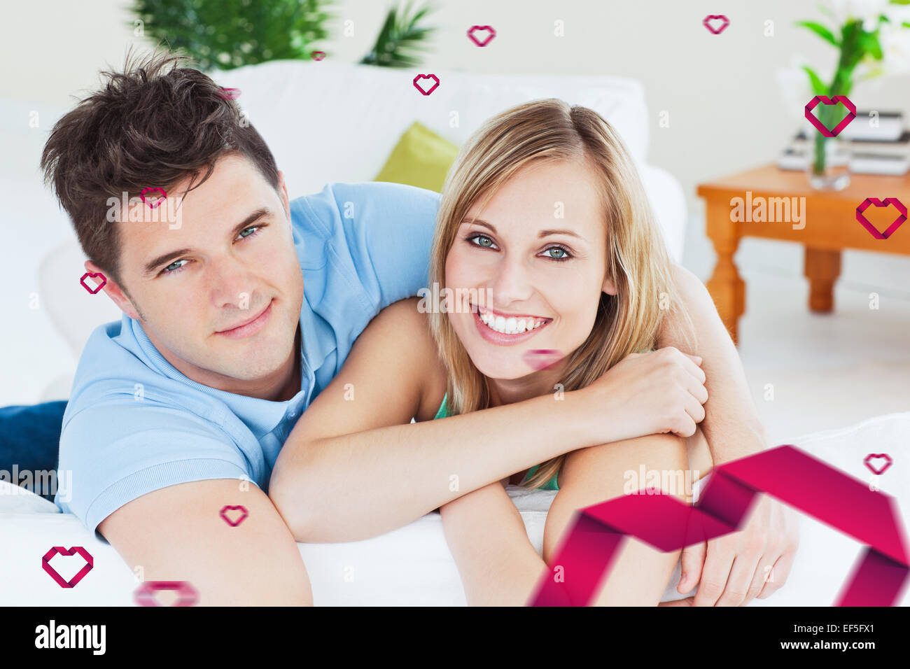 Composite image of smiling beatiful couple sitting on a sofa Stock Photo