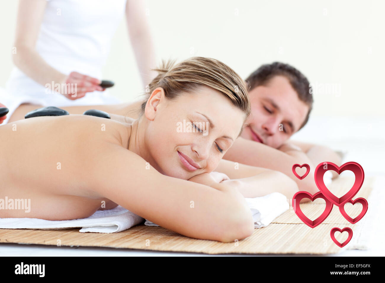 Composite image of young couple having a massage with hot stone Stock Photo