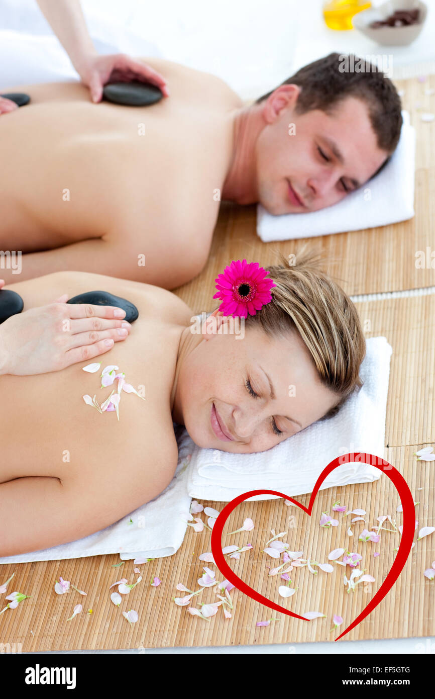 Composite image of young couple enjoying a back massage with stone Stock Photo