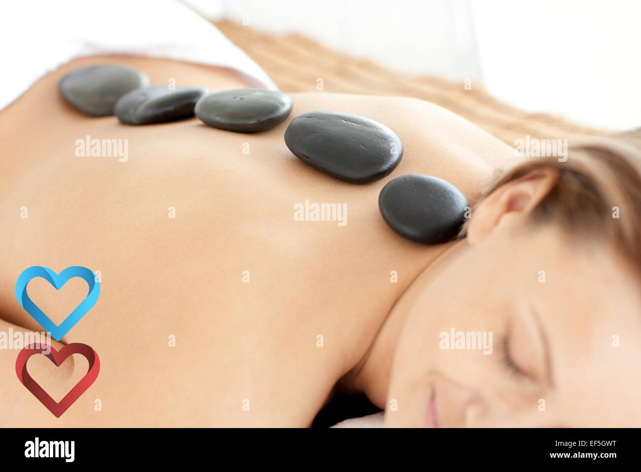 Composite image of relaxed woman with hot stones on her back Stock Photo