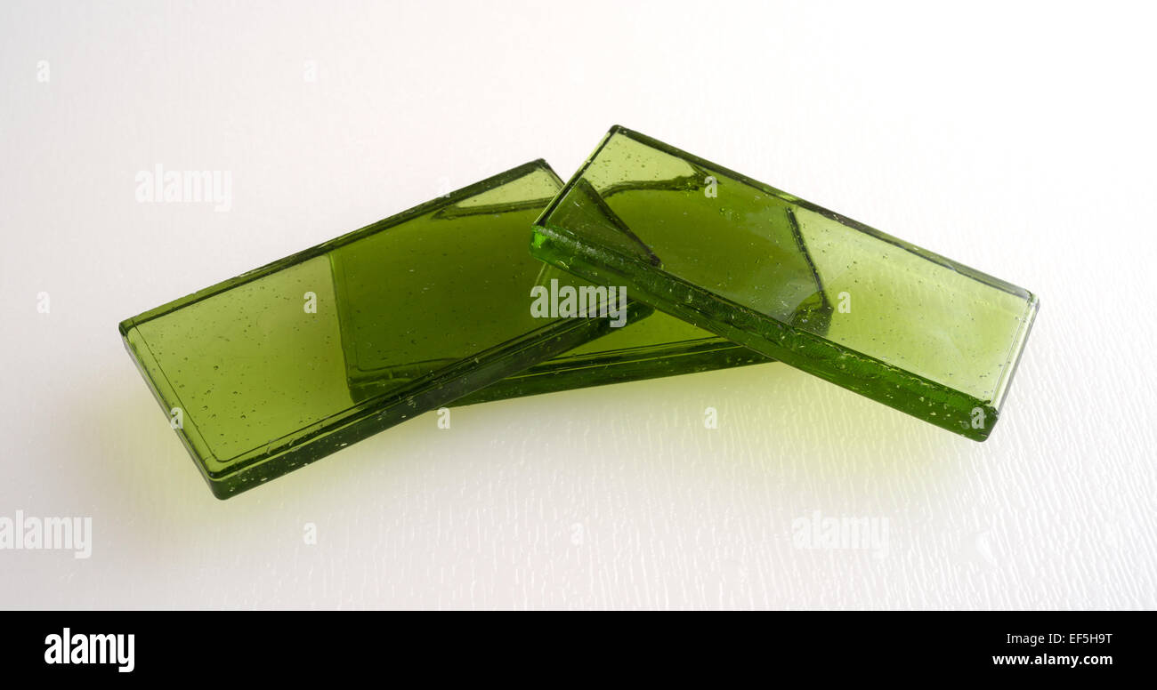 Three green tinted glass tiles on a white background illuminated by natural light. Stock Photo