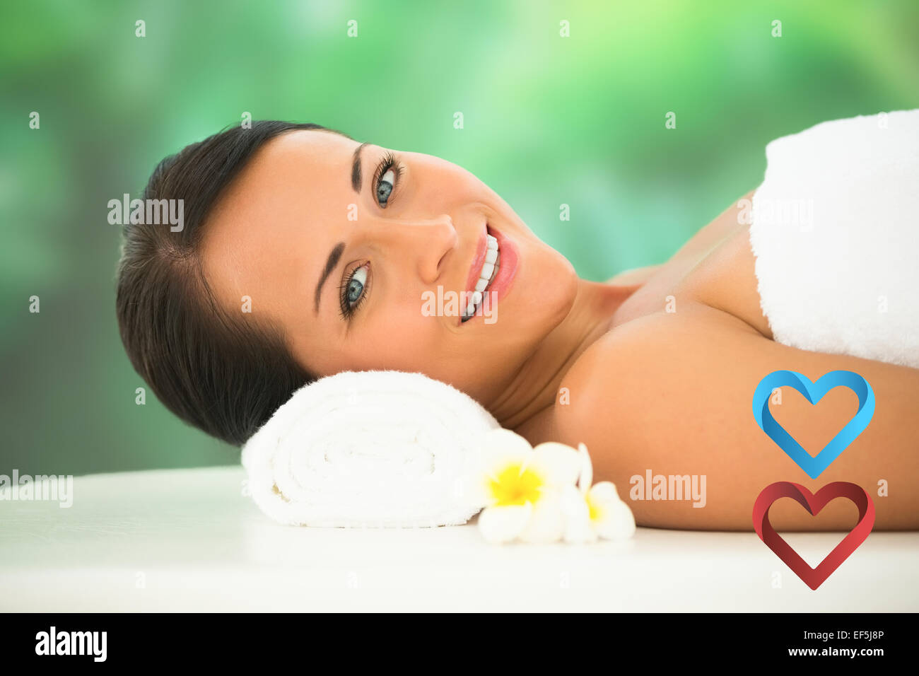 Composite image of beautiful brunette relaxing on massage table smiling at camera Stock Photo