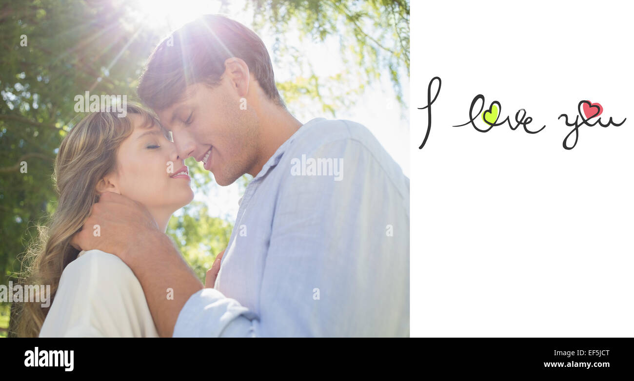Composite image of cute couple hugging and smiling in the park Stock ...