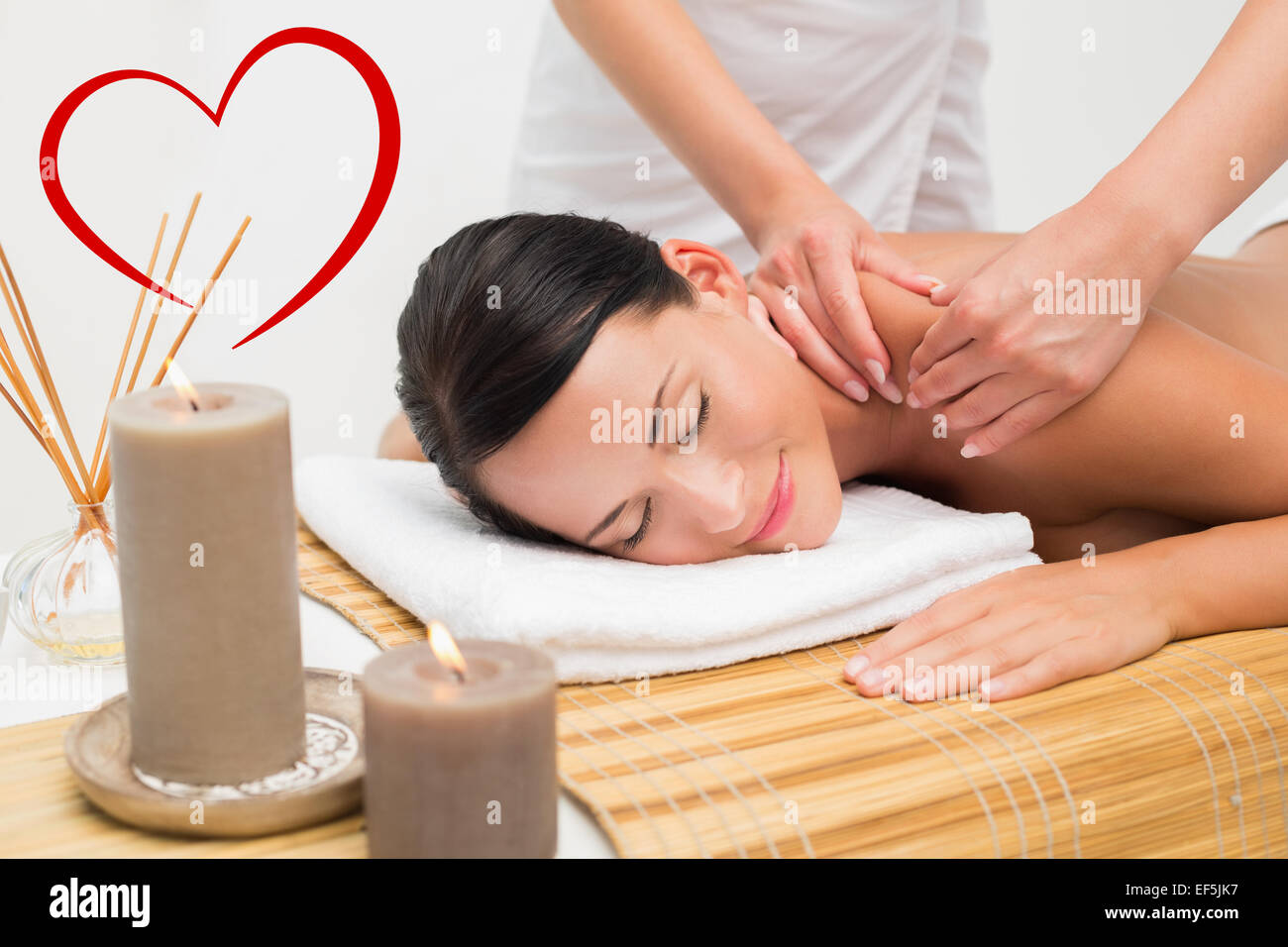 Composite image of beautiful brunette enjoying a shoulder massage smiling at camera Stock Photo