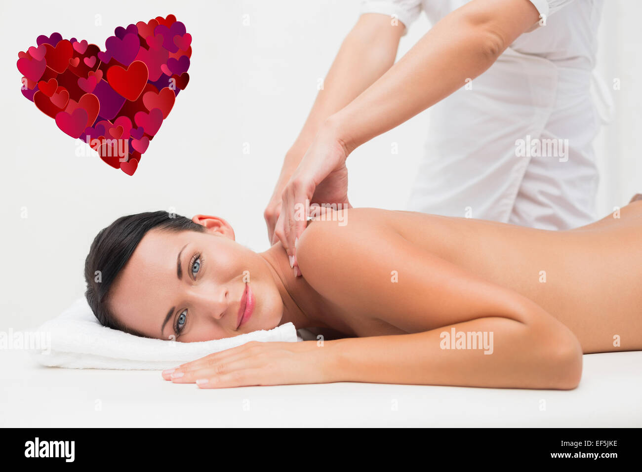 Composite image of beautiful brunette enjoying a back massage smiling at camera Stock Photo