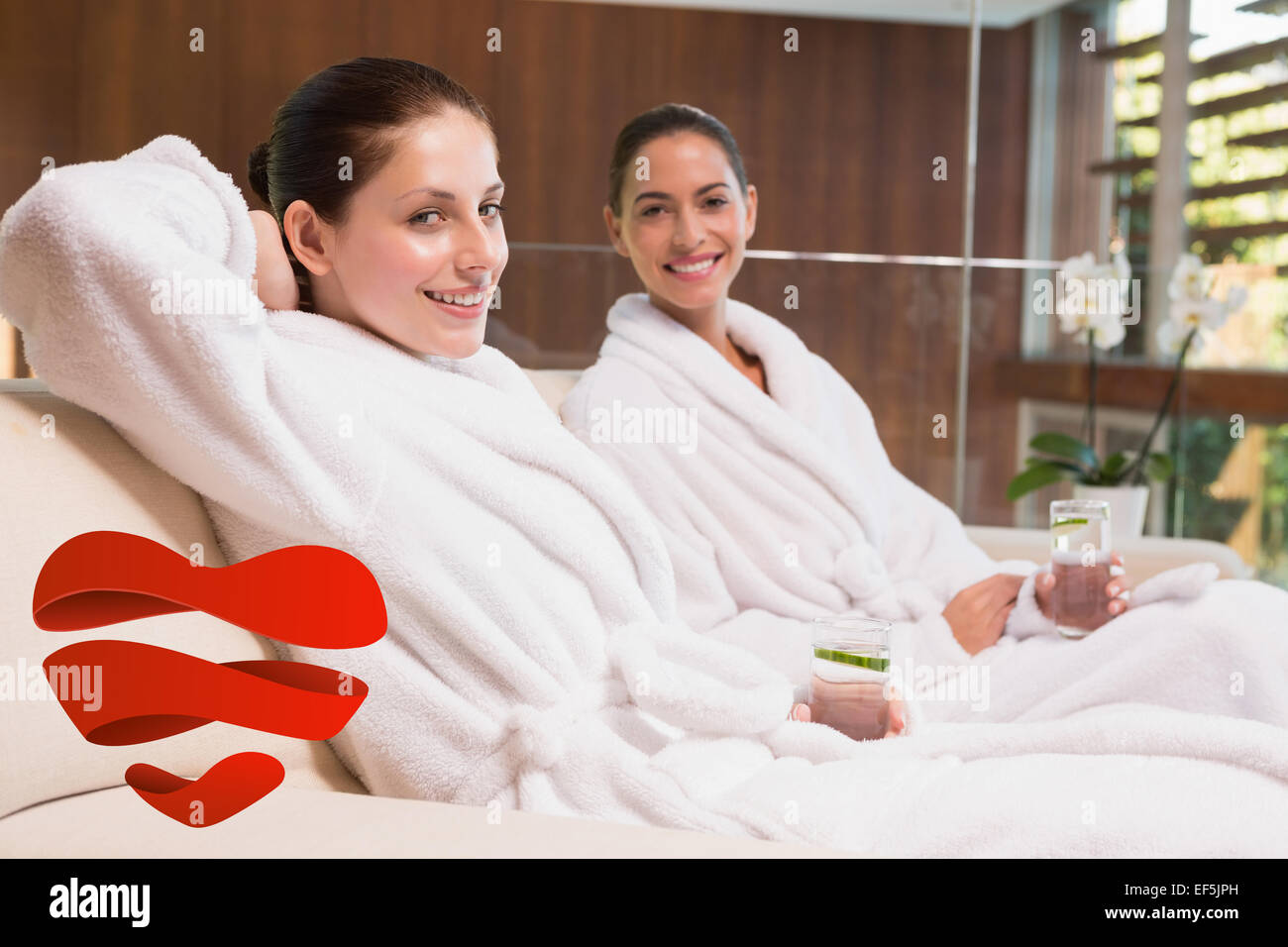Composite image of smiling women in bathrobes sitting on couch Stock Photo