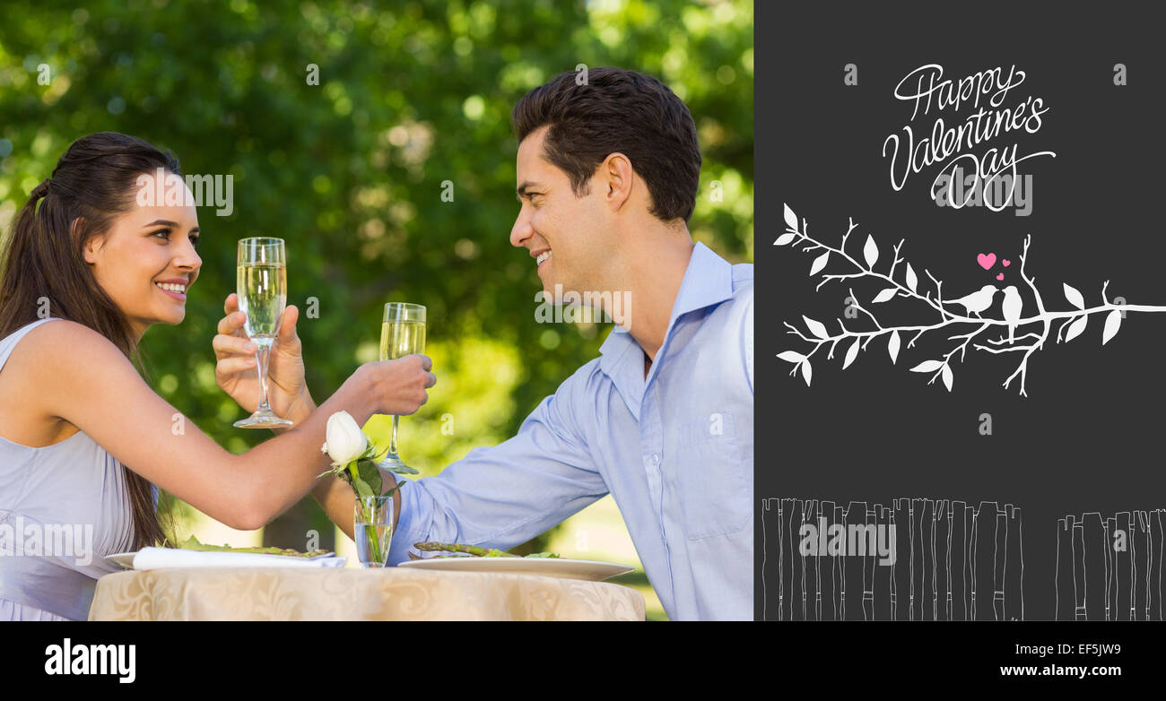 Composite image of couple with champagne flutes sitting at outdoor cafÃ© Stock Photo