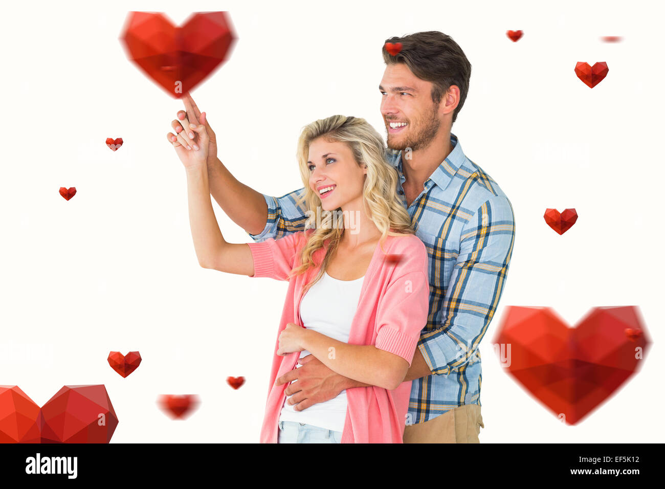 Composite image of attractive young couple embracing and pointing Stock ...