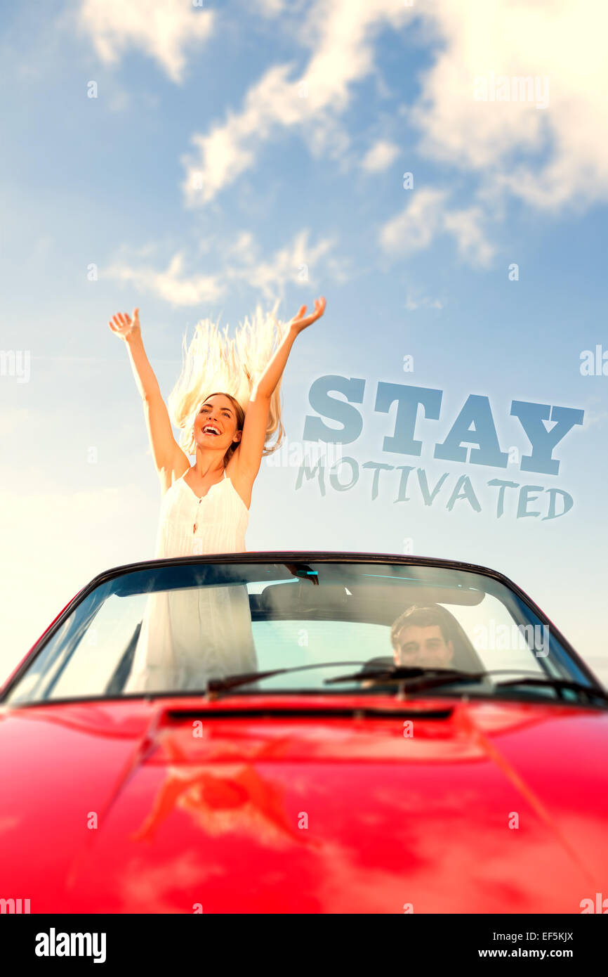 Composite image of happy woman standing in cabriolet while her boyfriend driving Stock Photo