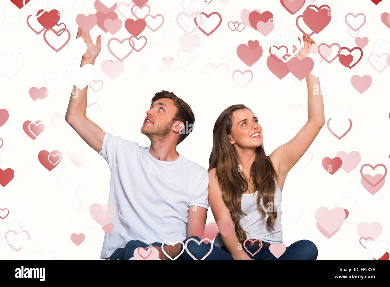 Composite image of happy young couple with hands raised Stock Photo