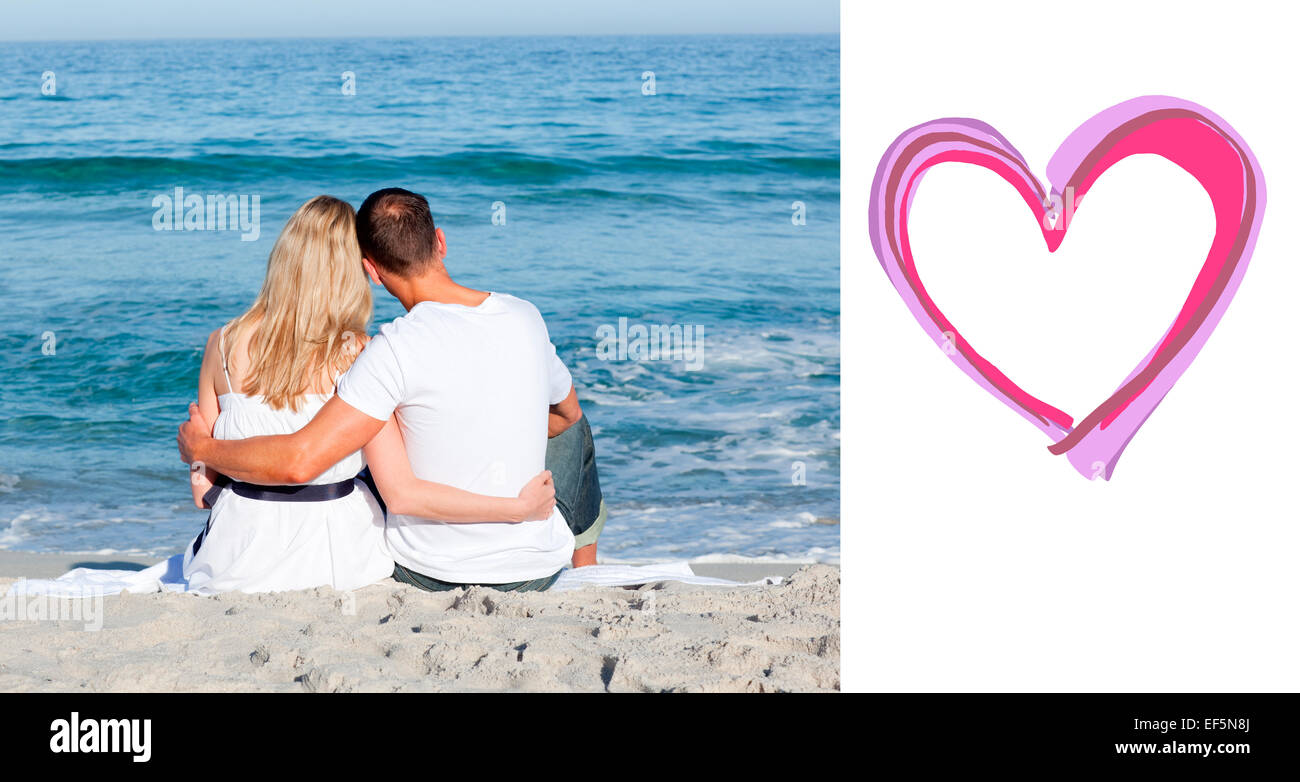 Composite image of affectionate couple sitting on the sand at the beach Stock Photo