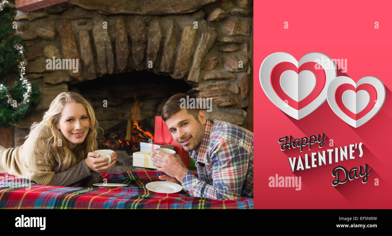Composite image of couple with tea cups in front of lit fireplace Stock Photo