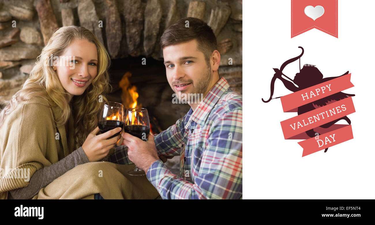 Composite image of romantic couple toasting wineglasses in front of lit fireplace Stock Photo