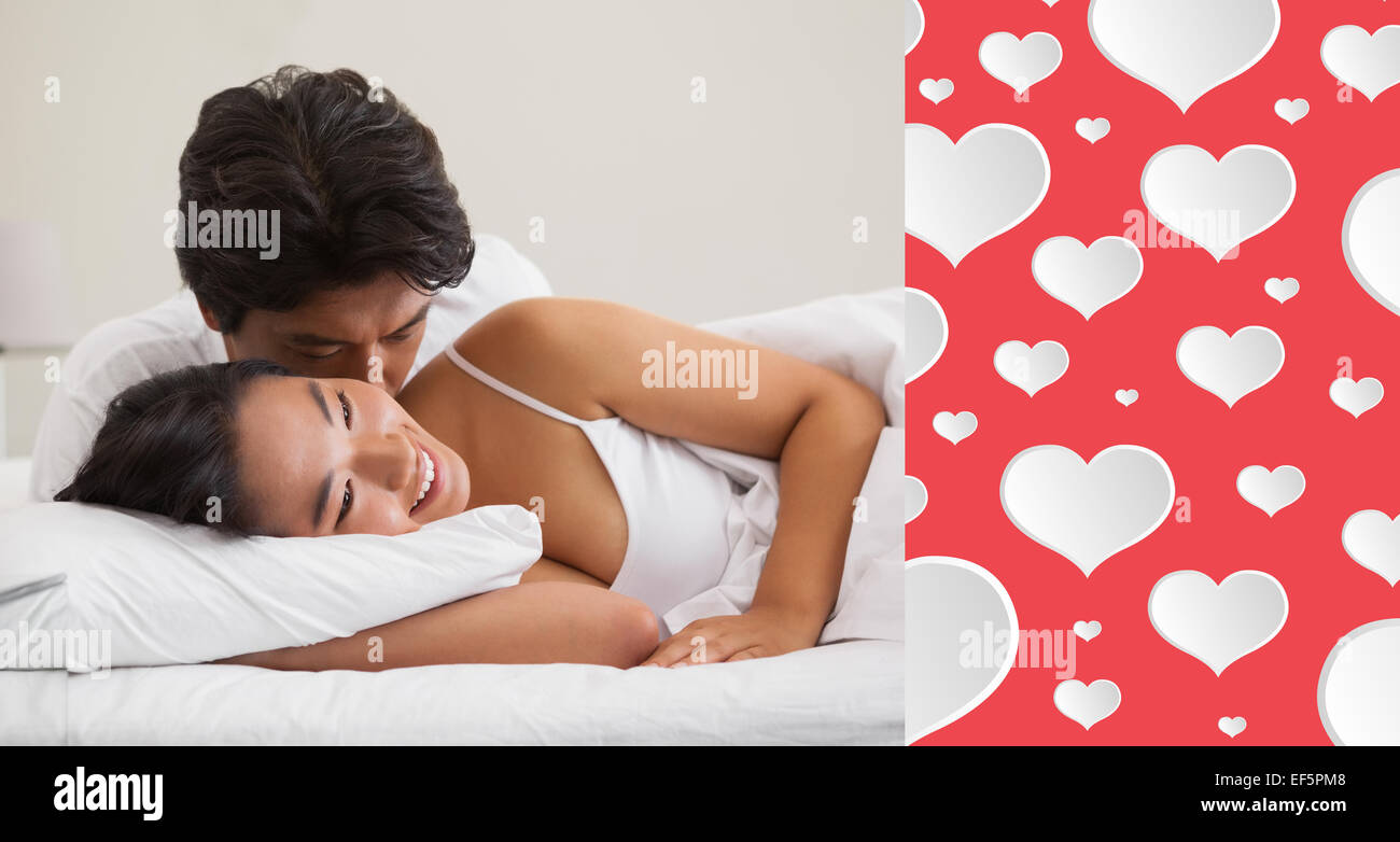 Composite image of couple lying in bed and cuddling Stock Photo