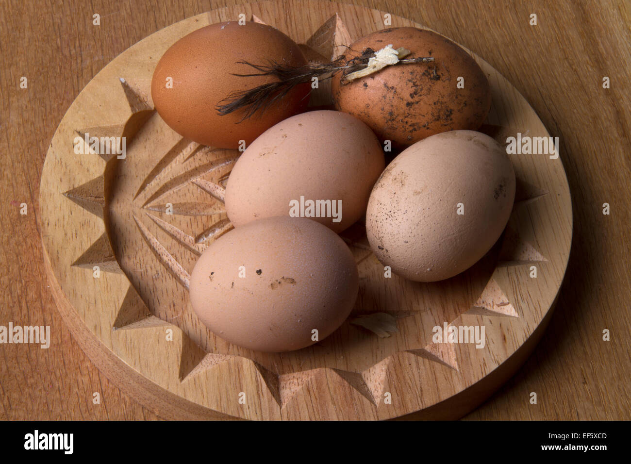 Freshly laid, unwashed chicken's eggs on a wooden dish Stock Photo