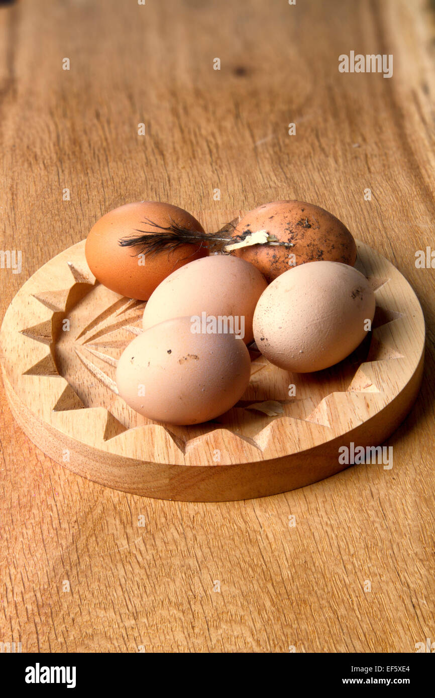 Freshly laid, unwashed chicken's eggs on a wooden dish Stock Photo