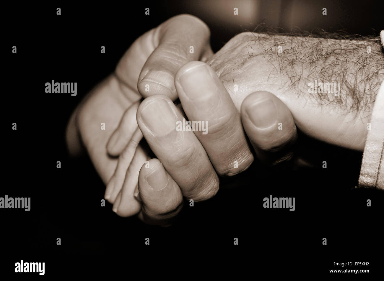 closeup of a young man holding the hand of an old man, in black and ...
