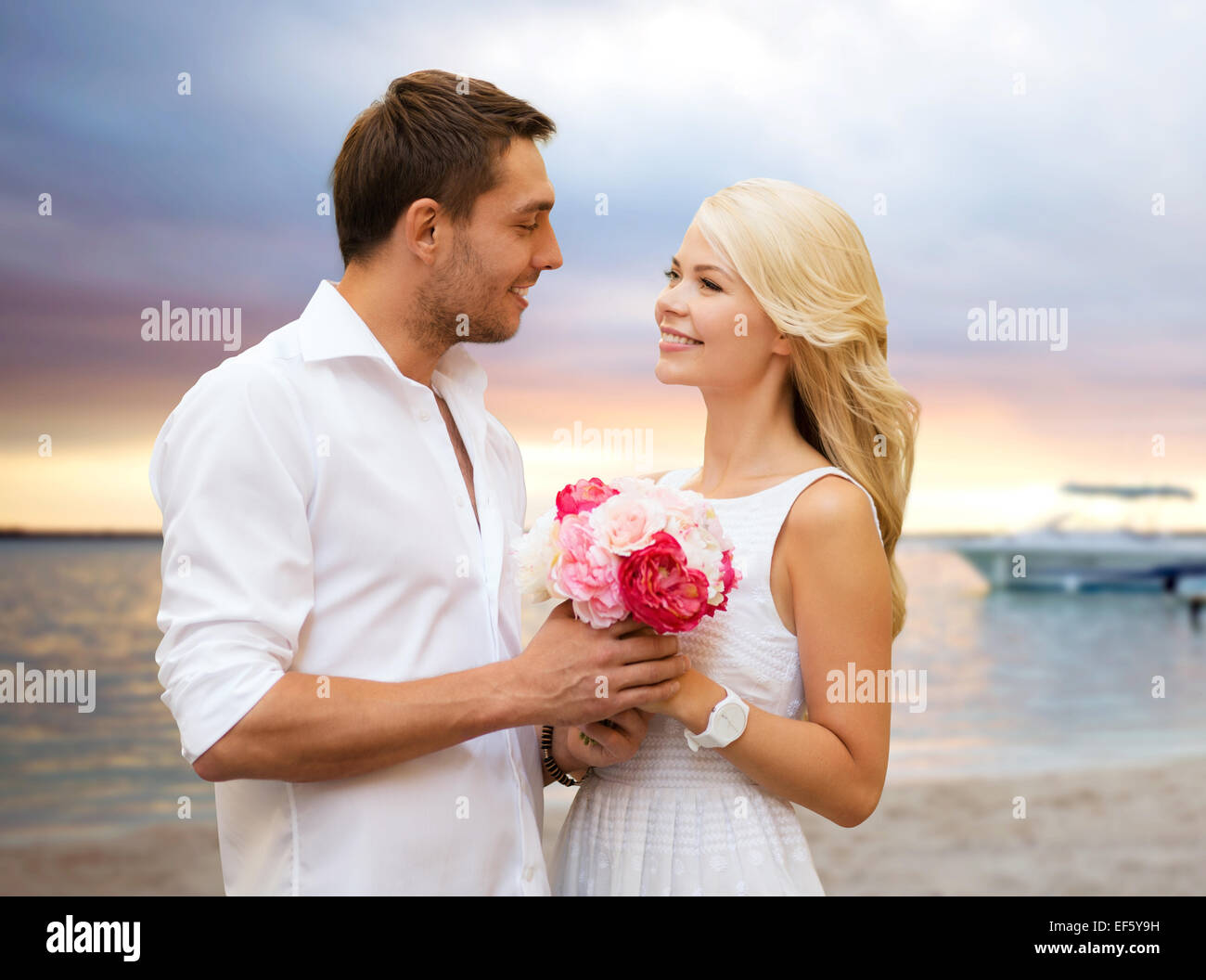 happy couple with flowers over beach background Stock Photo - Alamy