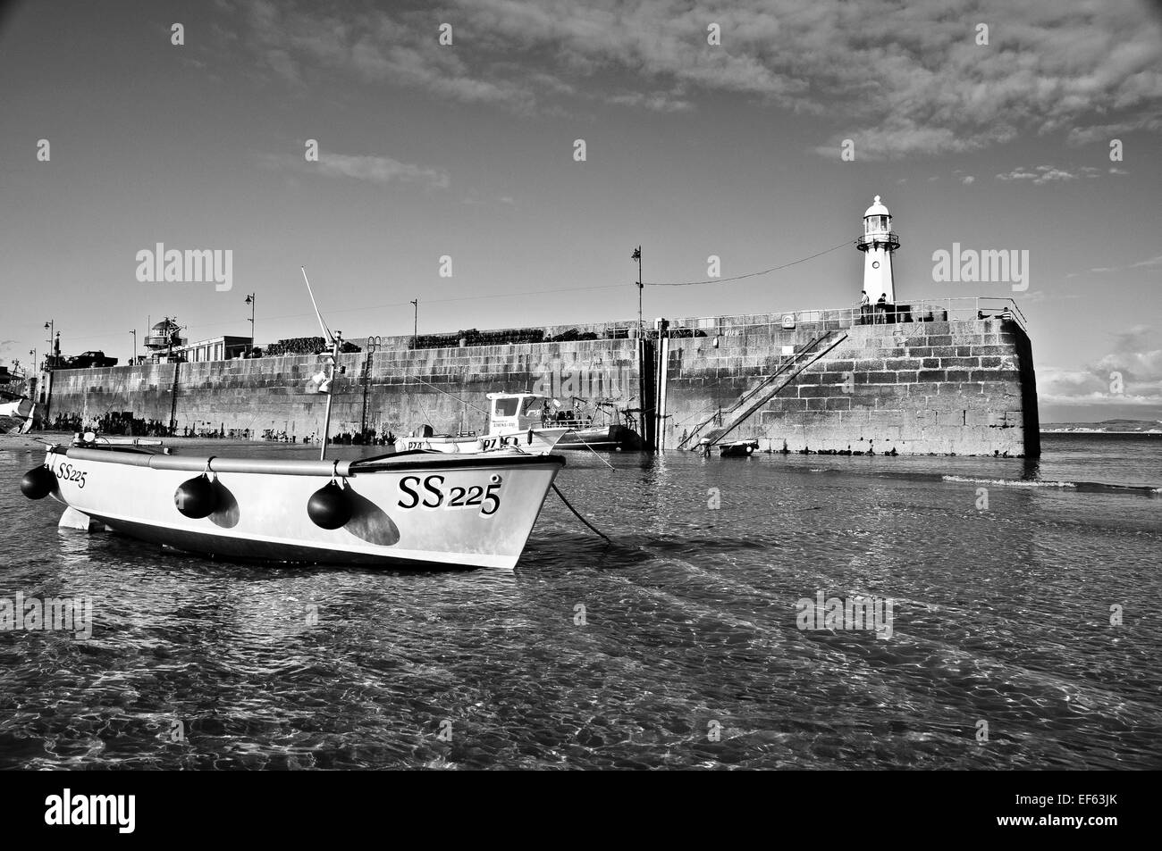 The SS225 rests peacefully in the shallow, crystal clear waters of the St. Ives harbour with the lighthouse watching on. Stock Photo