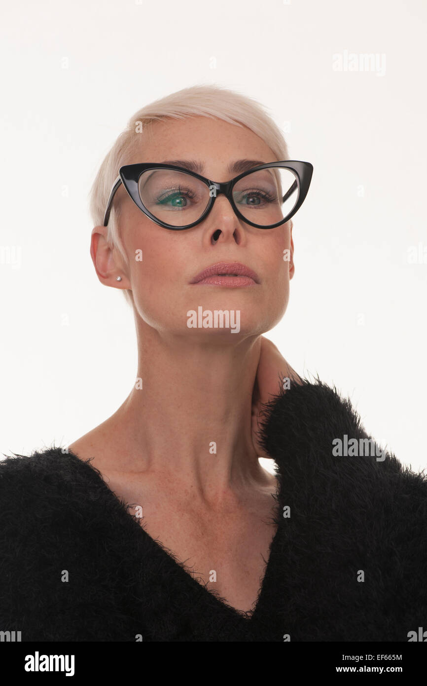 mature woman wearing big framed black glasses with short blonde hair Stock Photo