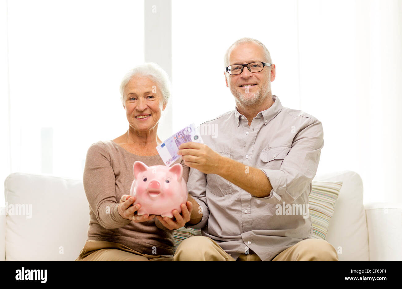 senior couple with money and piggy bank at home Stock Photo - Alamy