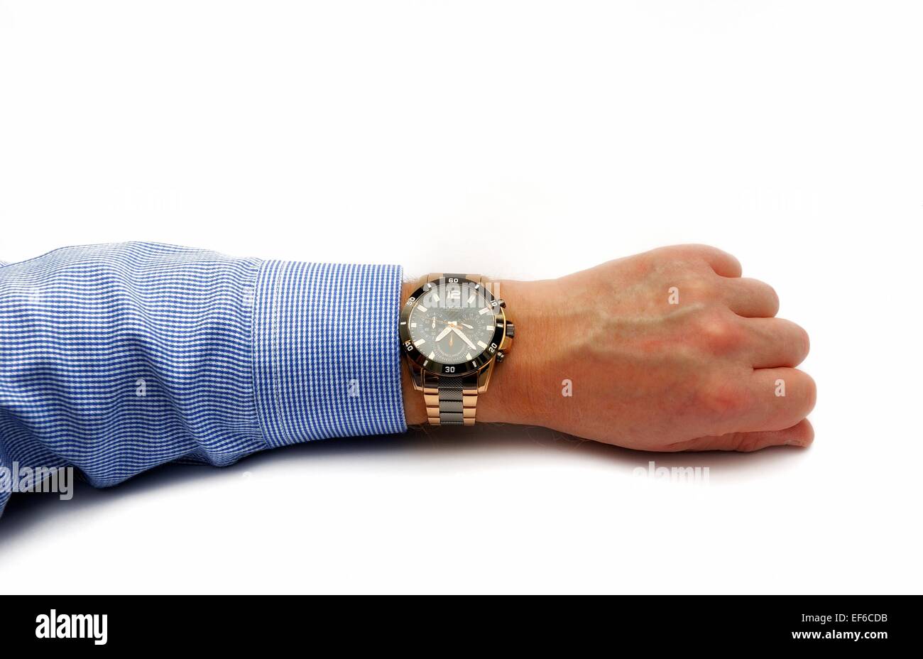 A man's arm wearing a wrist watch and a blue formal shirt on a white