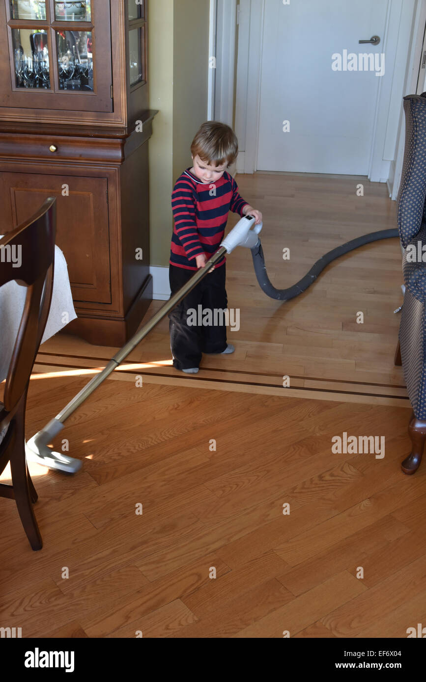 A young boy ( 2 1/2 years) doing the hoovering Stock Photo