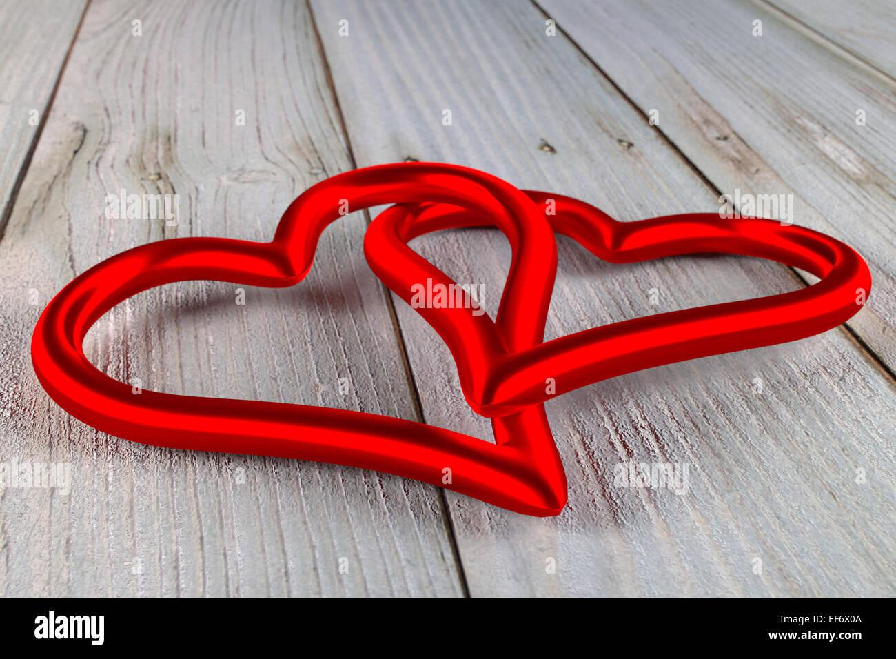 two red shining interwined hearts on a old planks Stock Photo