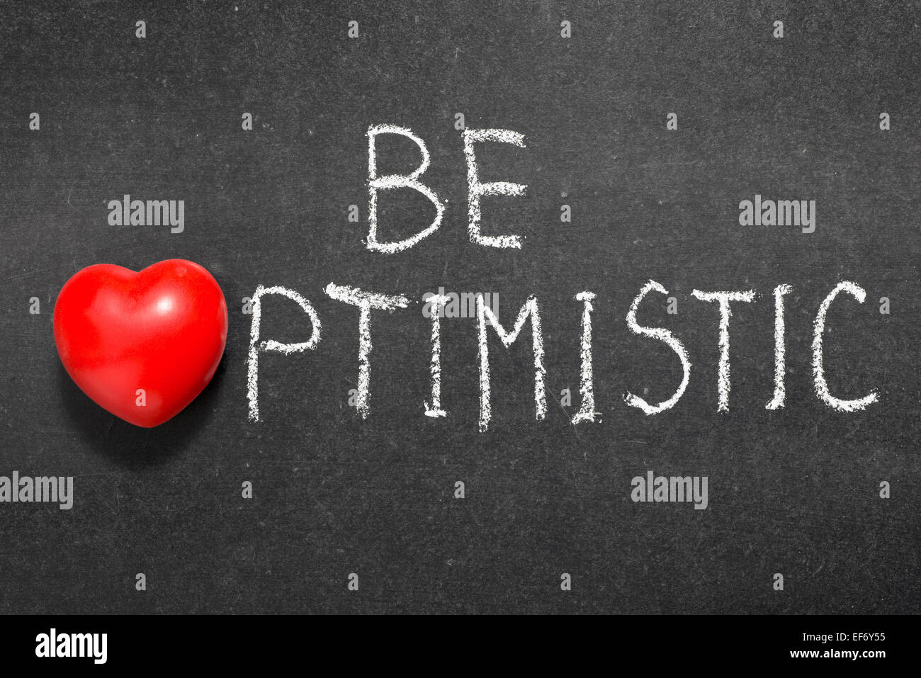 be optimistic phrase handwritten on blackboard with heart symbol instead of O Stock Photo
