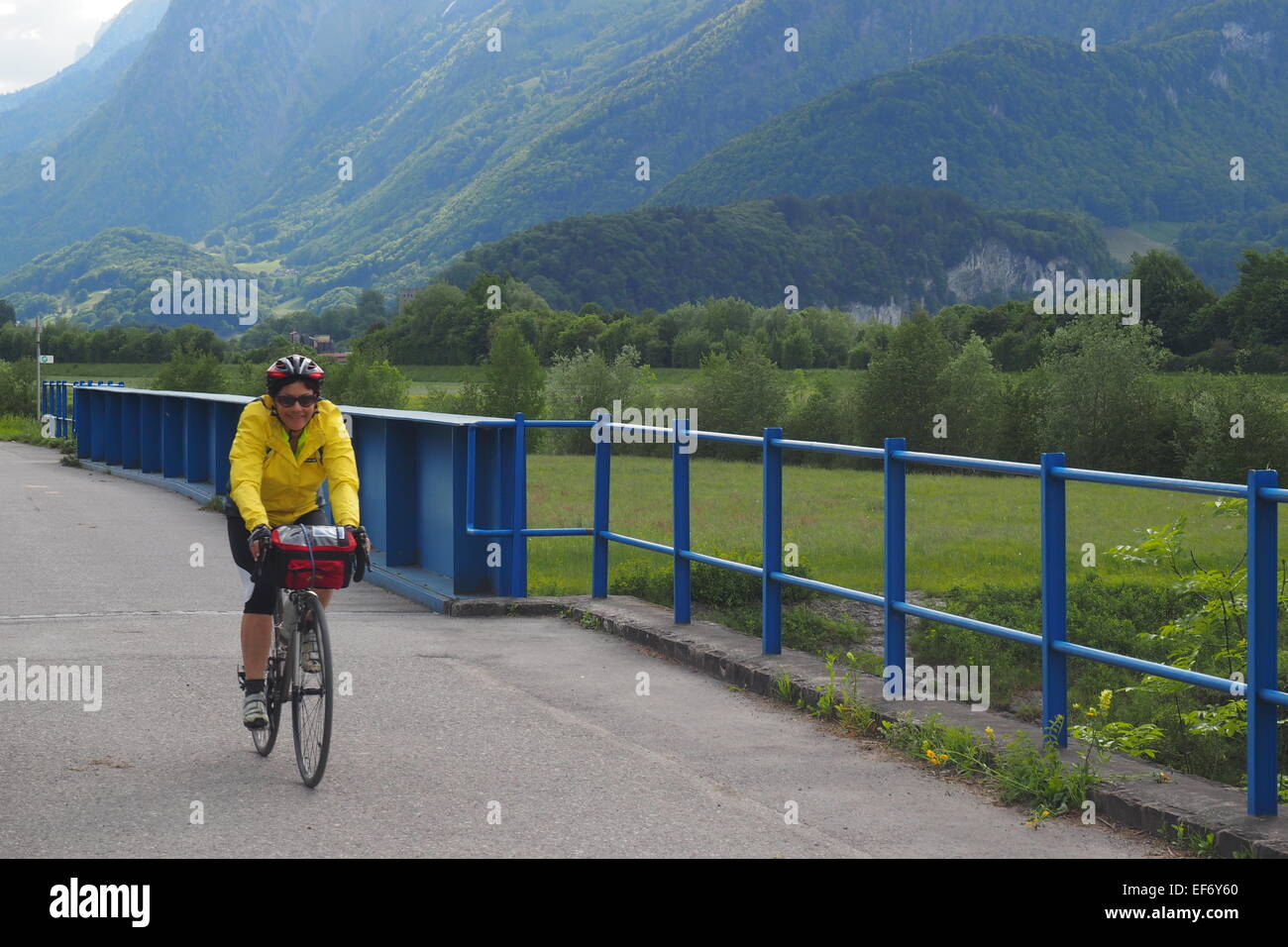 Touring female cyclist riding on a path way in Switzerland. Stock Photo