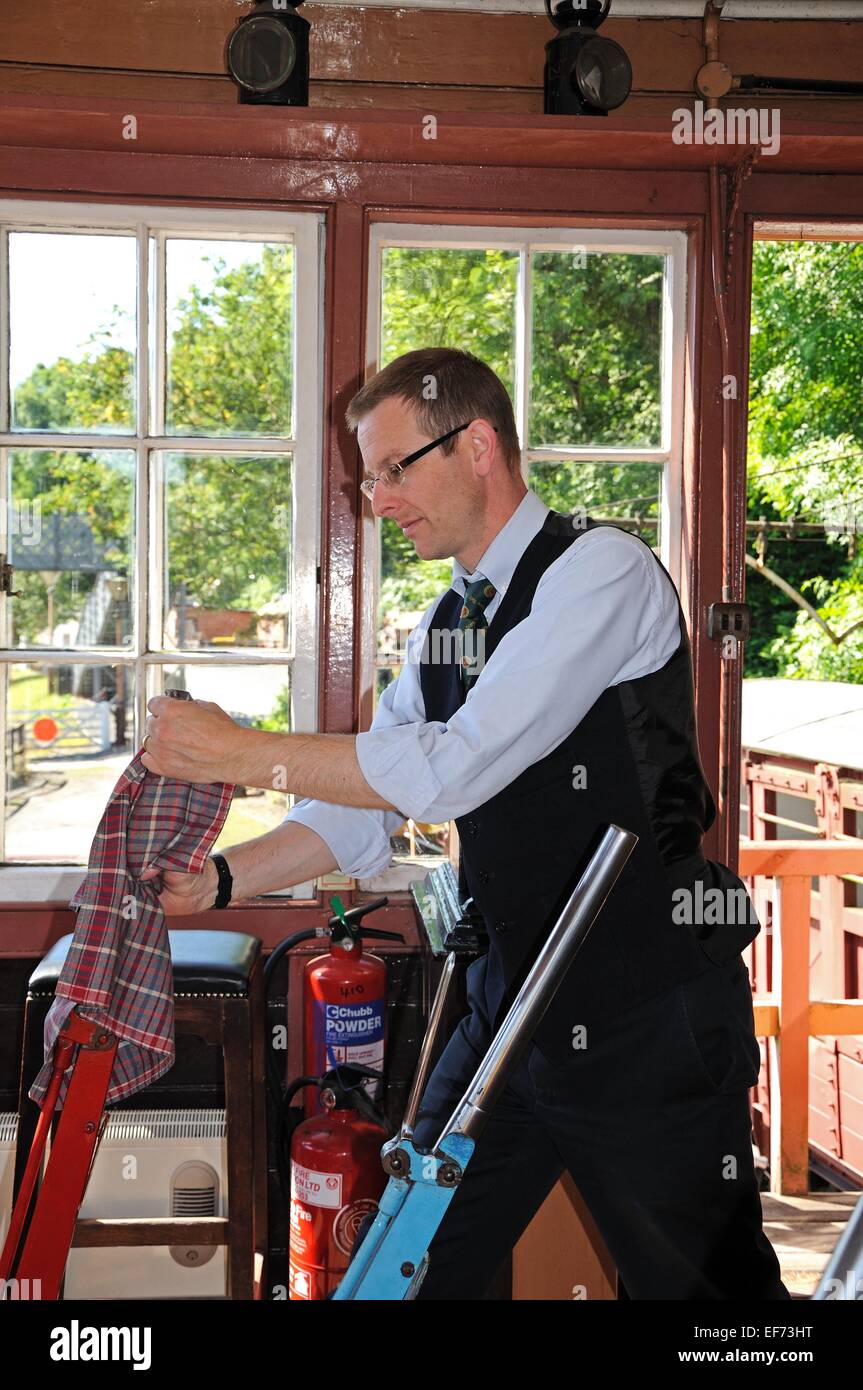 Signalman operating the Main Line lever on the mechanical lever frame inside the signal box at the railway station, Highley, UK. Stock Photo