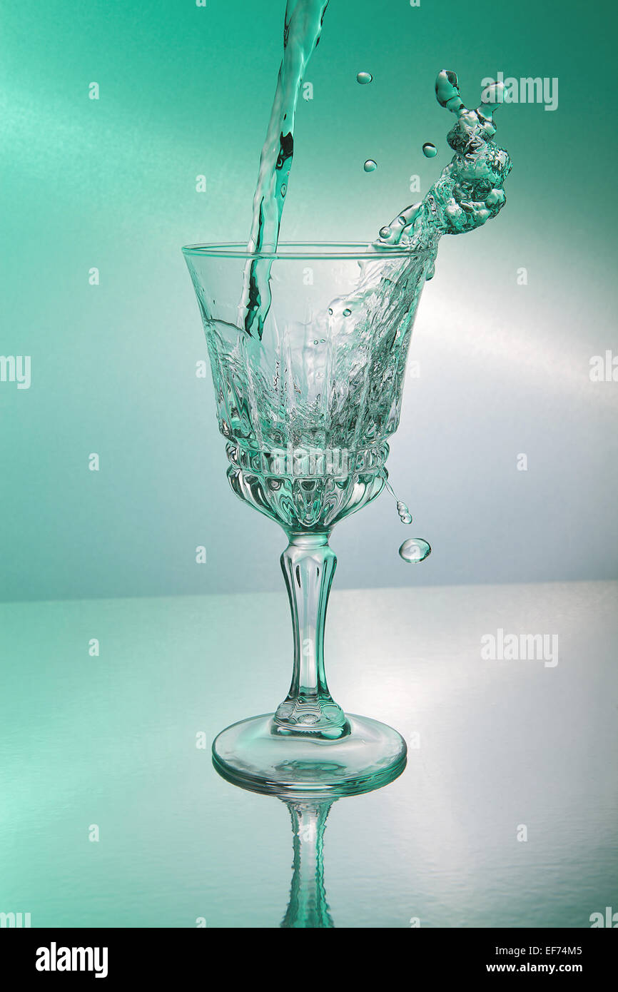 Water being poured into a glass and partly gushing from the glass Stock Photo