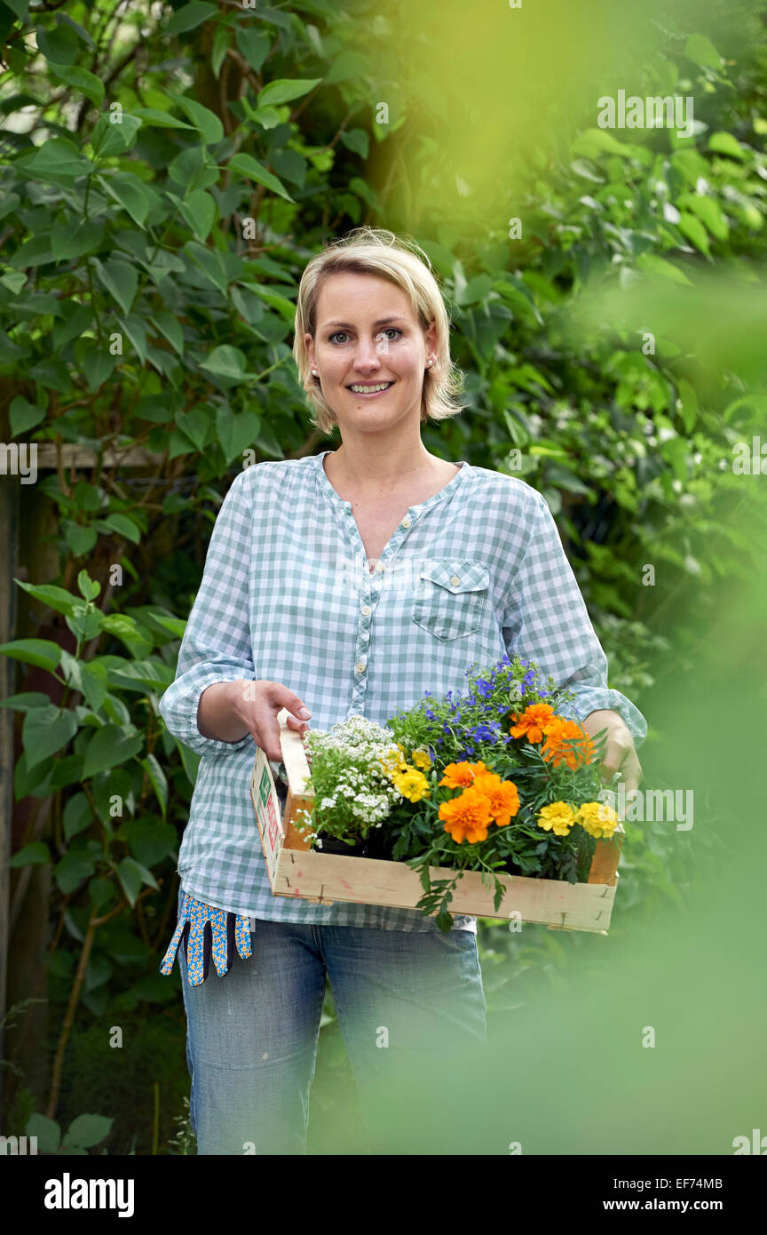 Woman in the garden with a basket full of plants Stock Photo - Alamy