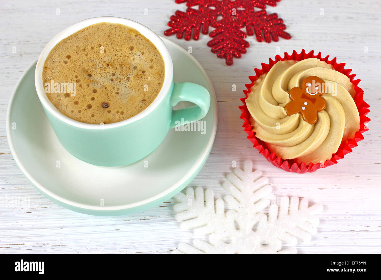 Holiday Coffee and cupcake on a rustic white wood background with glittering snowflake decorations. Stock Photo