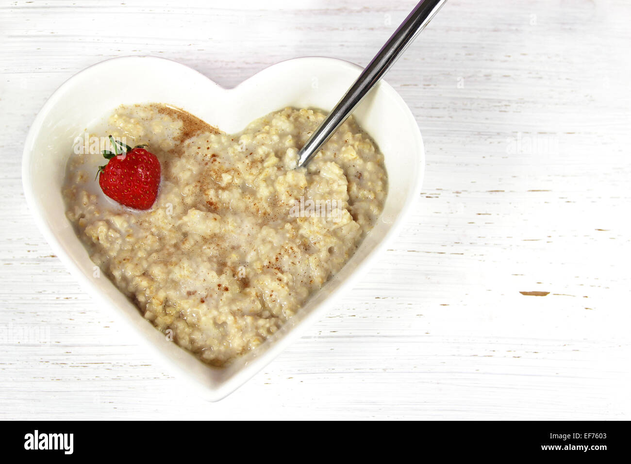 Porridge or Oatmeal in a heart shaped bowl with a strawberry garnish. Set  on a rustic white wood background Stock Photo - Alamy