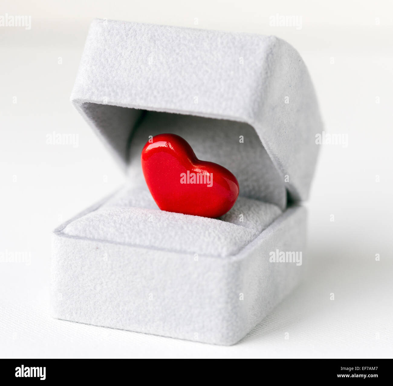 An image of a bright red ceramic heart inside a grey jewelry box, symbolizing a romantic proposal Stock Photo