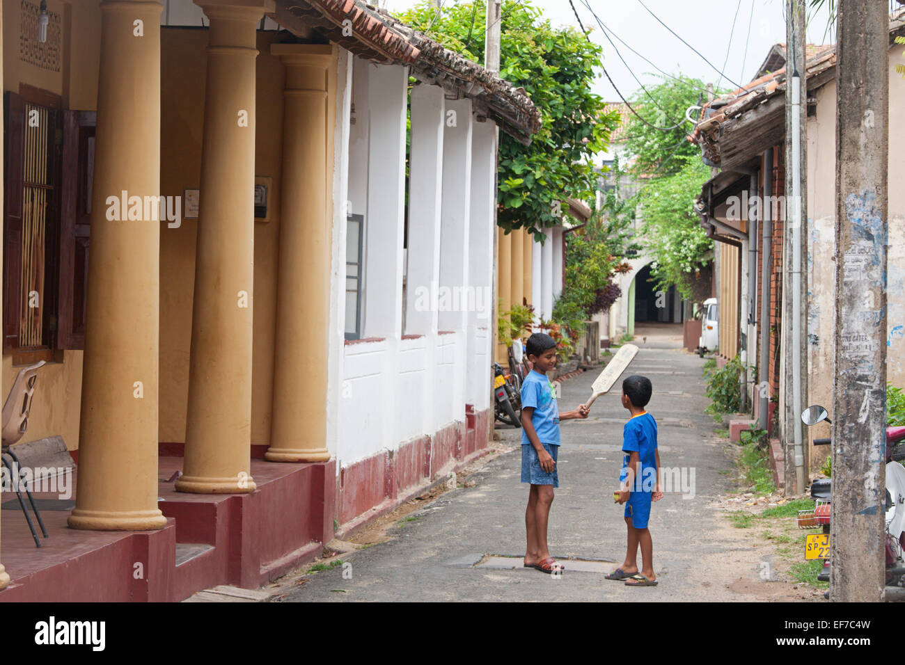 BOYS PLAYING CRICKET IN COLONIAL STREET IN GALLE FORT Stock Photo
