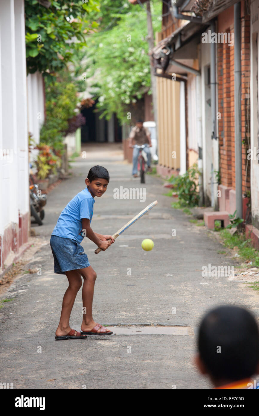 BOYS PLAYING CRICKET IN COLONIAL STREET IN GALLE FORT Stock Photo
