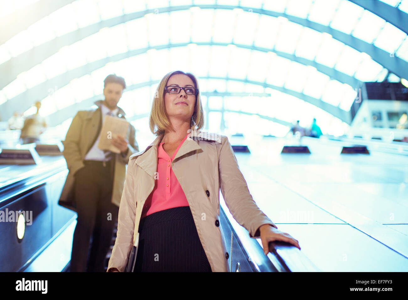 Businesswoman riding escalator Stock Photo