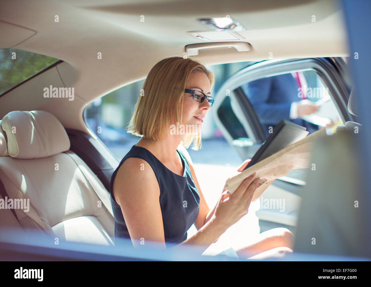 Businesswoman using digital tablet in back seat of car Stock Photo