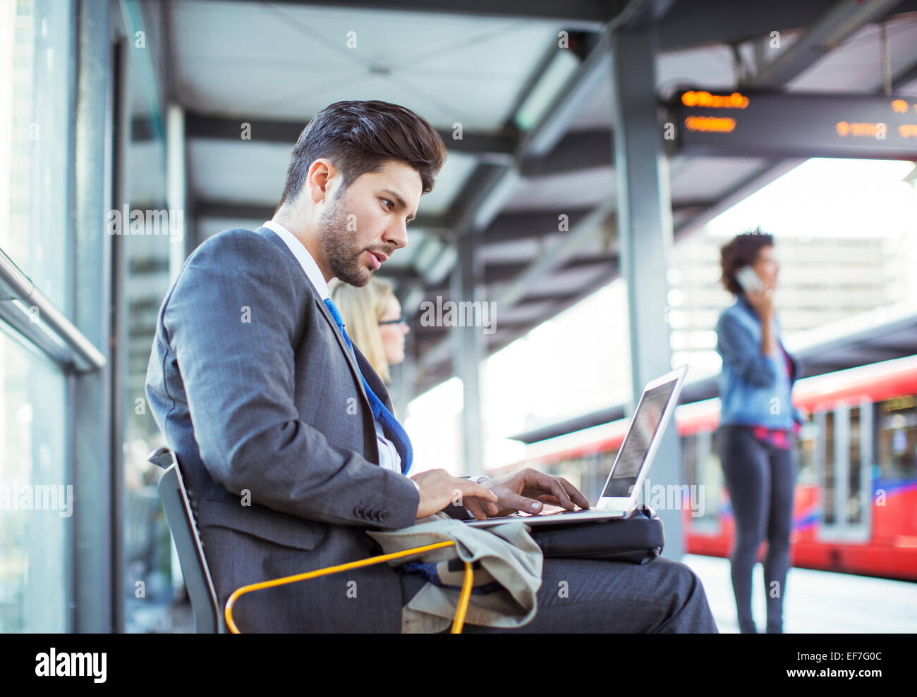 Businessman using laptop at train station Stock Photo