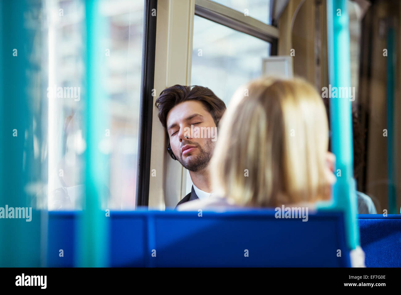 Businessman napping on train Stock Photo