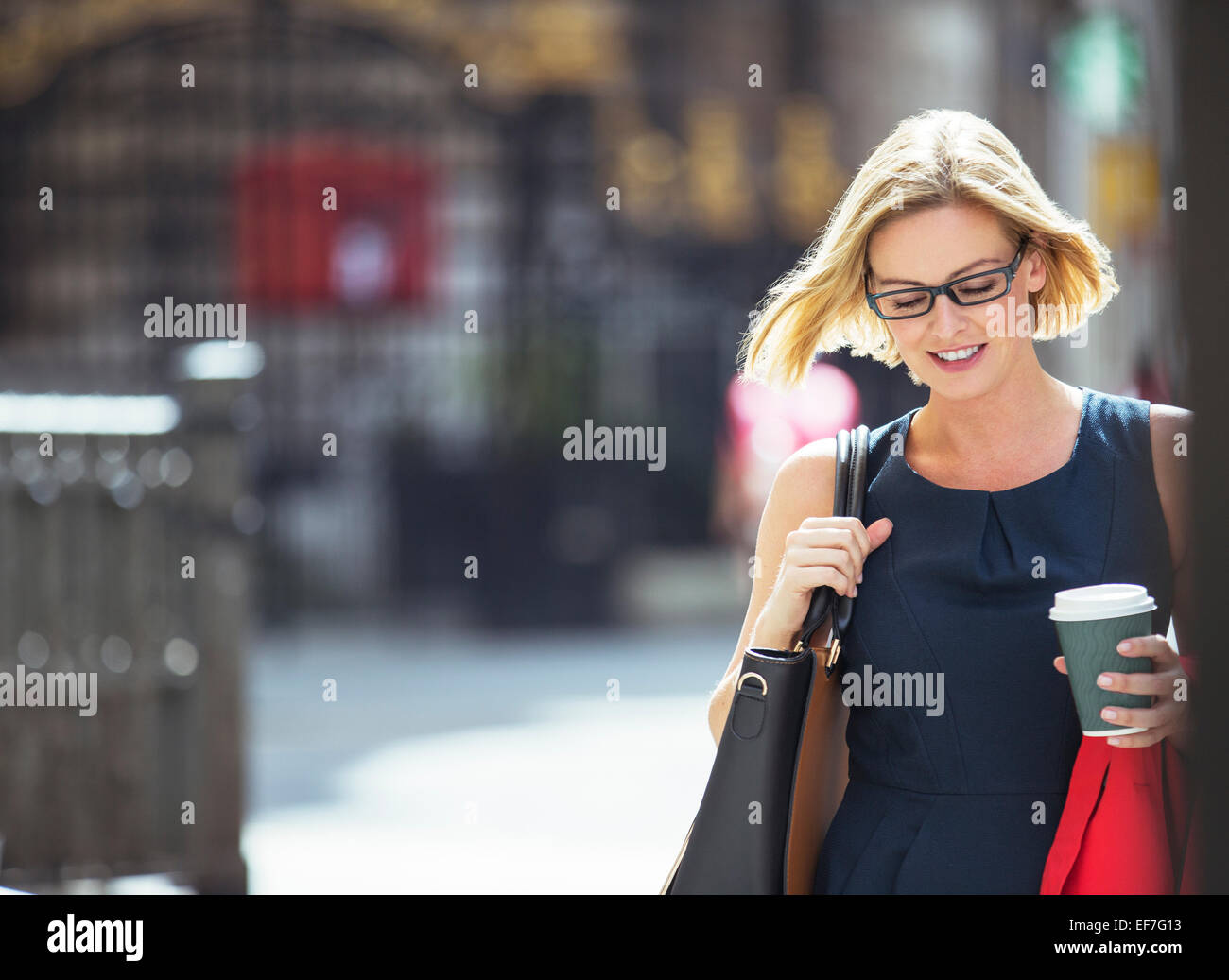 Businesswoman carrying cup of coffee in city Stock Photo