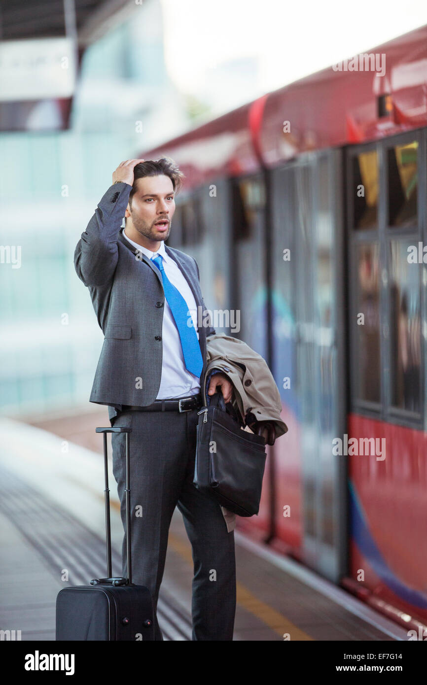 Frustrated businessman missing train in train station Stock Photo