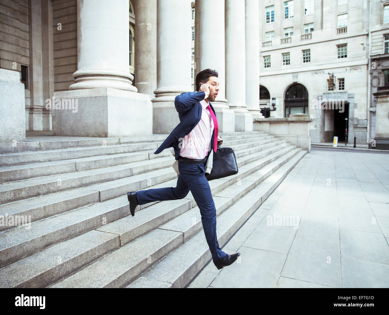 Businessman on cell phone running on city staircase Stock Photo