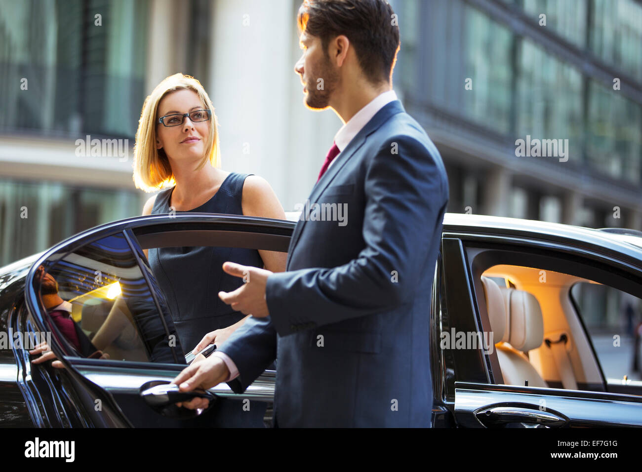 Chauffeur opening car door for businesswoman Stock Photo